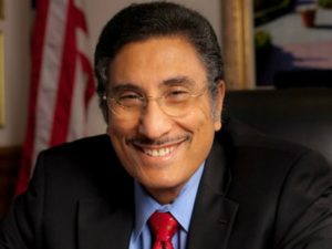 Michael Yousef wearing a black coat, smiling